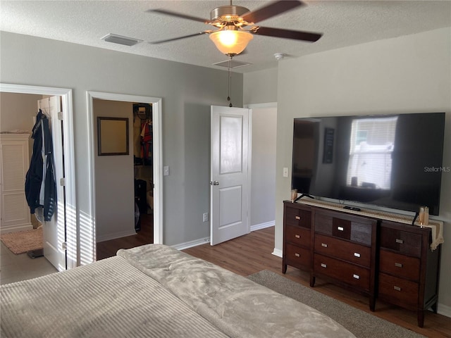 bedroom with ensuite bathroom, a walk in closet, hardwood / wood-style flooring, ceiling fan, and a closet