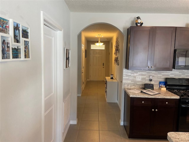 hall featuring light tile patterned floors and a textured ceiling