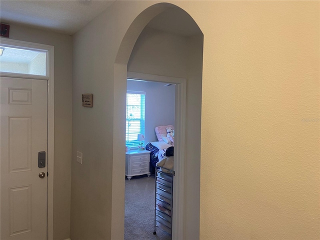 carpeted foyer entrance with a textured ceiling