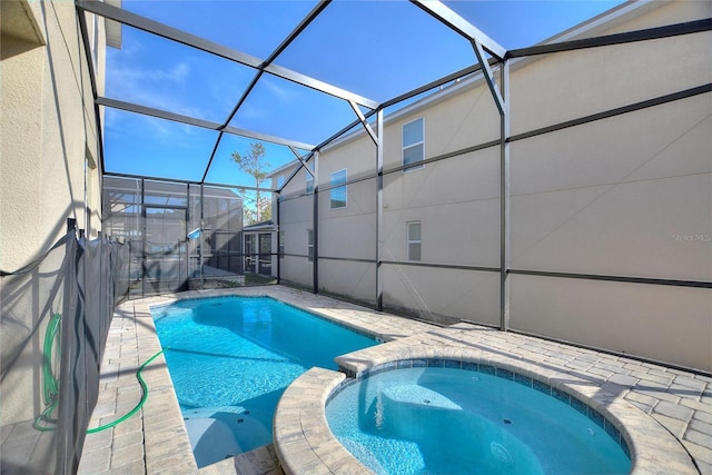 view of swimming pool with an in ground hot tub, glass enclosure, and a patio area