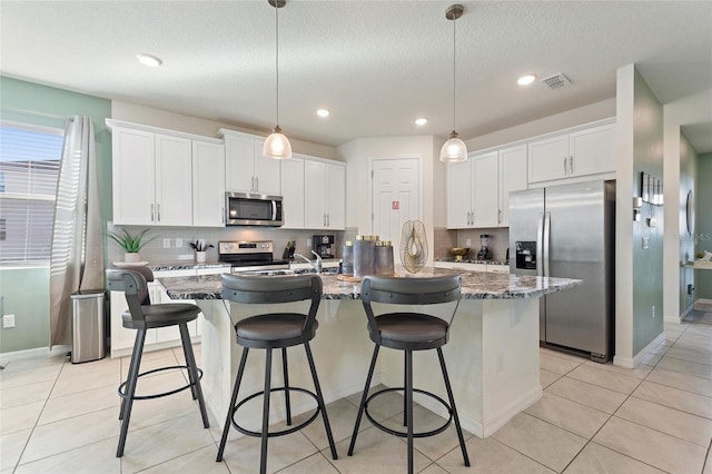 kitchen with white cabinetry, stainless steel appliances, and a kitchen island with sink