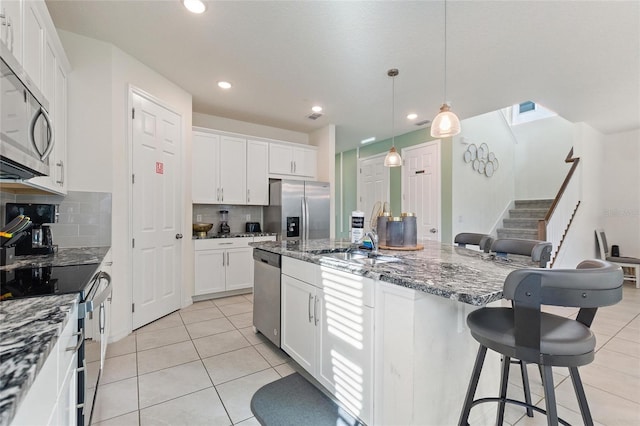 kitchen with pendant lighting, backsplash, dark stone countertops, appliances with stainless steel finishes, and white cabinetry