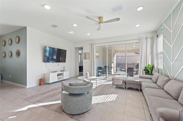 living room with ceiling fan, light tile patterned floors, and a textured ceiling