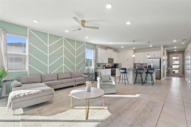 living room featuring ceiling fan, light tile patterned floors, and a textured ceiling