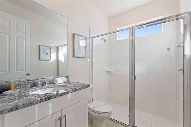 bathroom featuring tile patterned floors, vanity, toilet, and a shower with shower door