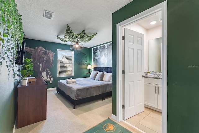 bedroom with ensuite bathroom, light colored carpet, and a textured ceiling