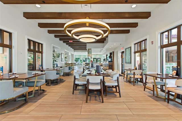 dining room featuring beam ceiling, plenty of natural light, and an inviting chandelier