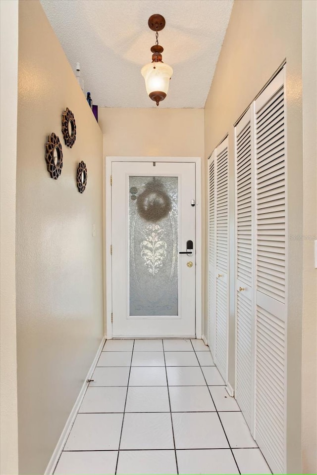 doorway with light tile patterned flooring and a textured ceiling