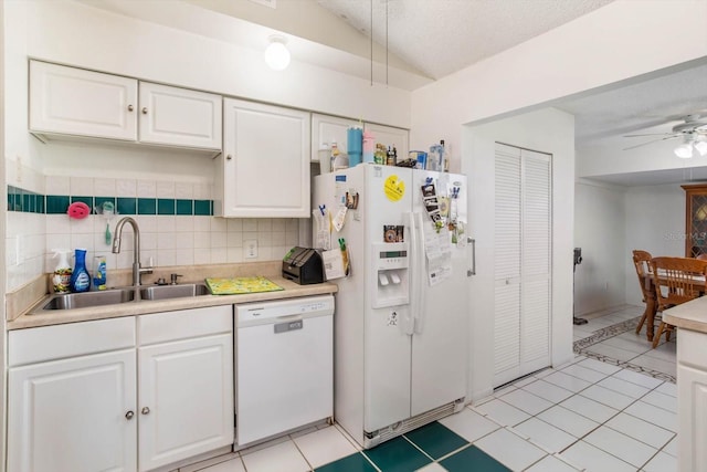 kitchen featuring backsplash, white appliances, sink, light tile patterned floors, and white cabinetry