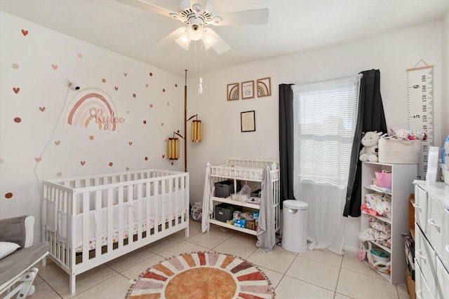 tiled bedroom featuring ceiling fan and a crib