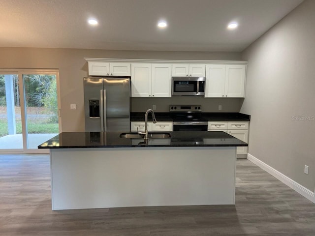 kitchen featuring a kitchen island with sink, sink, white cabinets, and appliances with stainless steel finishes