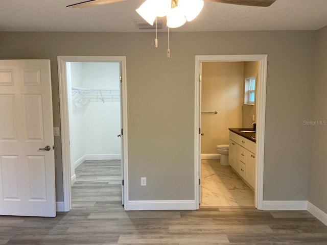 unfurnished bedroom with light wood-type flooring, a closet, a spacious closet, and ceiling fan