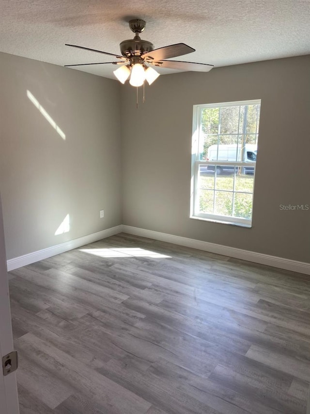 unfurnished room with a textured ceiling, ceiling fan, and dark wood-type flooring