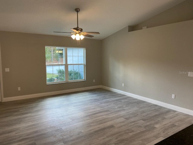 spare room with hardwood / wood-style flooring, vaulted ceiling, and ceiling fan