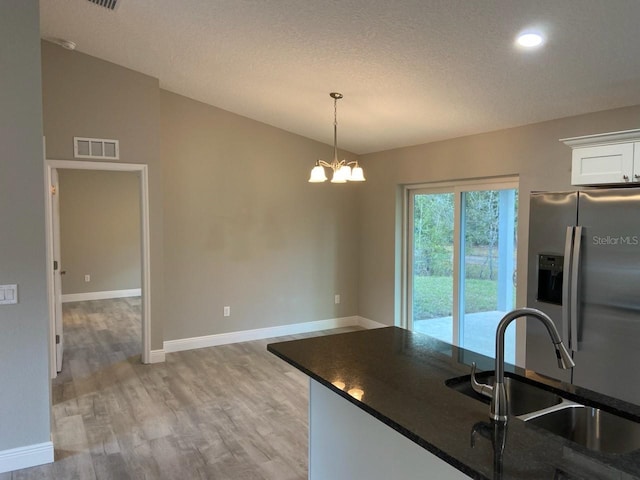 kitchen featuring light wood-type flooring, sink, a notable chandelier, white cabinetry, and hanging light fixtures