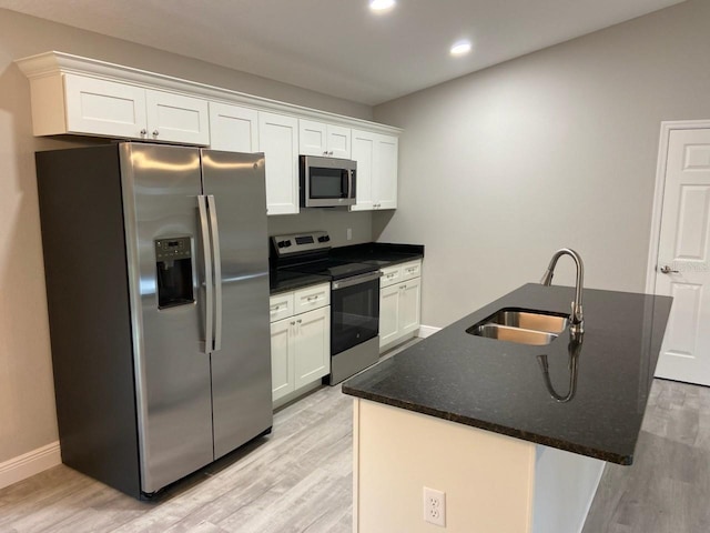 kitchen with an island with sink, sink, white cabinets, and stainless steel appliances