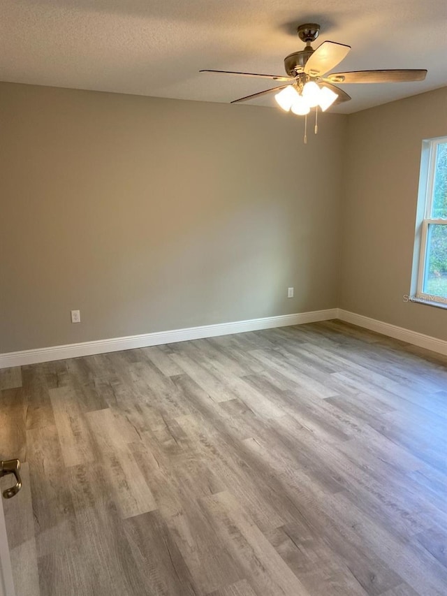 spare room with ceiling fan, a textured ceiling, and light wood-type flooring