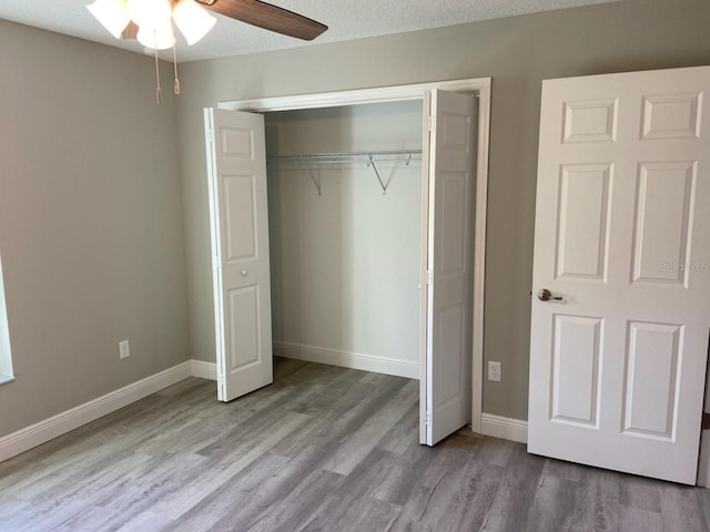 unfurnished bedroom with ceiling fan, a closet, a textured ceiling, and light hardwood / wood-style flooring