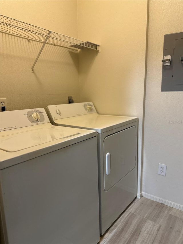 laundry room featuring washing machine and dryer, electric panel, and light hardwood / wood-style flooring