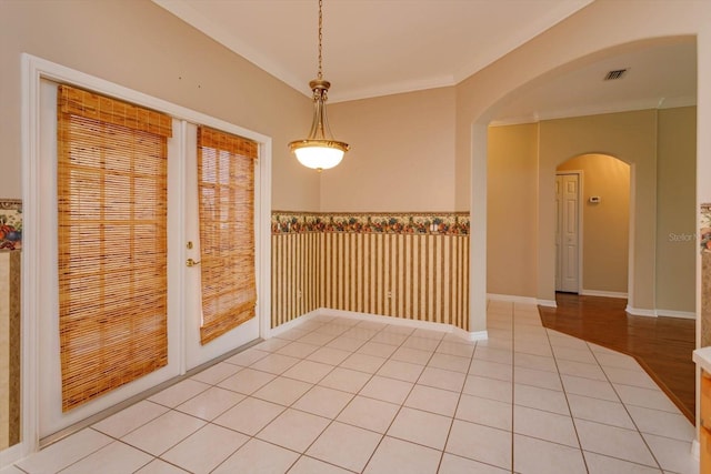 unfurnished dining area featuring light tile patterned floors, ornamental molding, and french doors