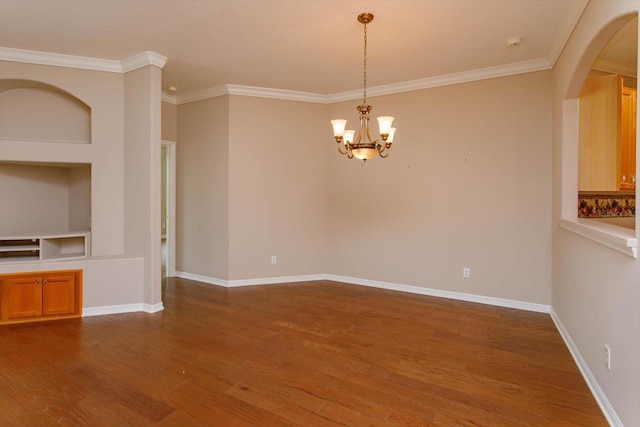 empty room with hardwood / wood-style floors, ornamental molding, and an inviting chandelier