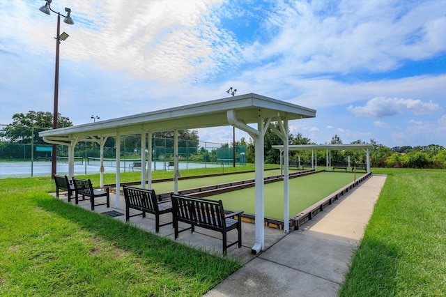 view of property's community with a water view, tennis court, and a yard