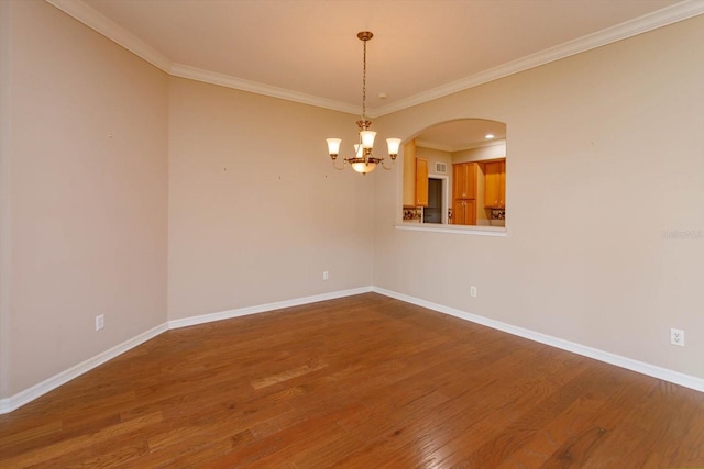 spare room featuring an inviting chandelier, ornamental molding, and hardwood / wood-style flooring