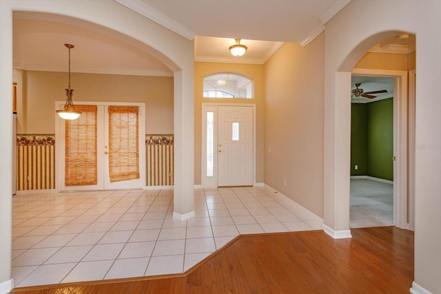 tiled foyer entrance with ceiling fan, ornamental molding, and french doors