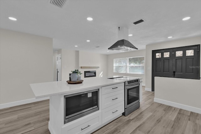 kitchen featuring a center island, light wood-type flooring, white cabinetry, and appliances with stainless steel finishes