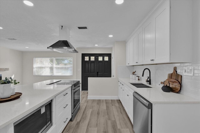 kitchen with sink, light hardwood / wood-style flooring, white cabinets, exhaust hood, and appliances with stainless steel finishes