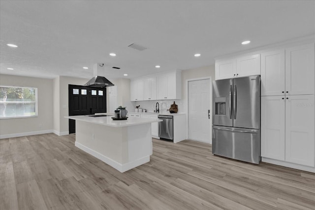 kitchen with white cabinets, light hardwood / wood-style floors, a kitchen island, and stainless steel appliances