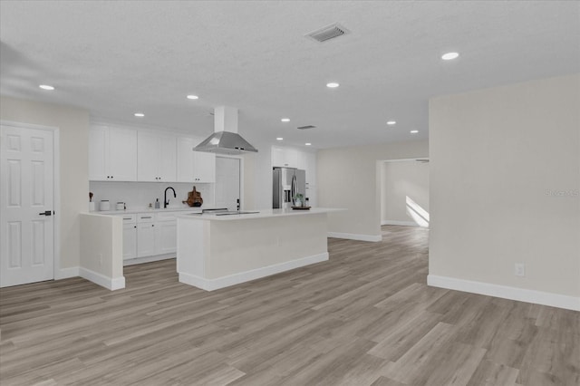 kitchen with white cabinets, light hardwood / wood-style flooring, an island with sink, range hood, and stainless steel fridge with ice dispenser