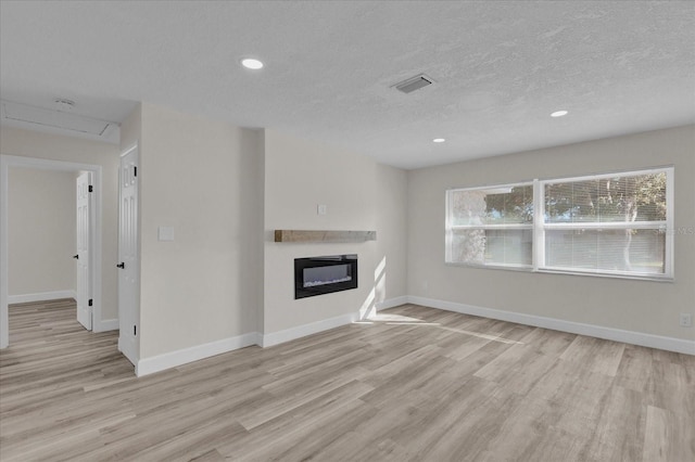 unfurnished living room featuring light hardwood / wood-style floors and a textured ceiling