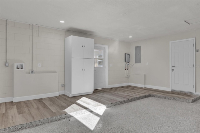 interior space with a textured ceiling, light wood-type flooring, and electric panel