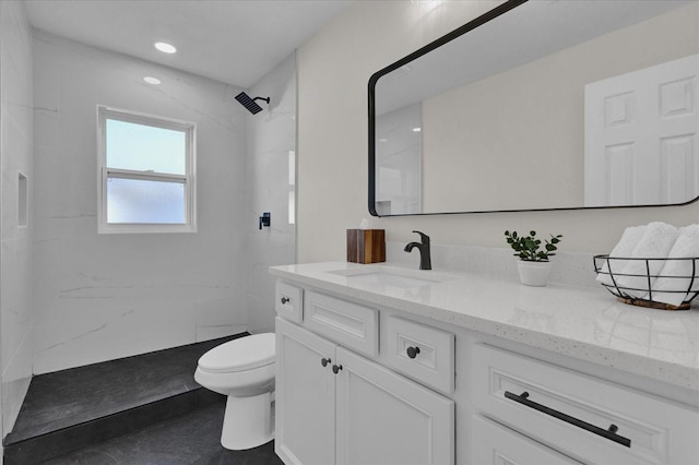 bathroom featuring vanity, toilet, and tiled shower