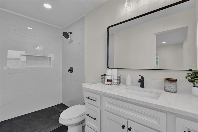 bathroom with vanity, toilet, and a tile shower