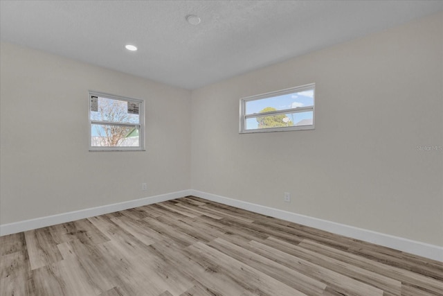 spare room featuring plenty of natural light, a textured ceiling, and light hardwood / wood-style flooring