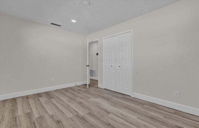 unfurnished bedroom featuring a closet, light hardwood / wood-style floors, and a textured ceiling