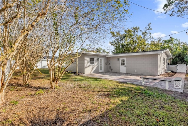 back of property featuring a patio area and a lawn