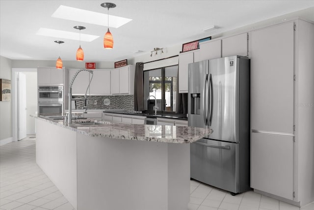 9 Crow Ct, Palm Coast, FL 32137 - kitchen with appliances with stainless steel finishes, a skylight, tasteful backsplash, light tile patterned floors, and white cabinets