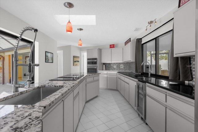 9 Crow Ct, Palm Coast, FL 32137 - kitchen featuring a skylight, beverage cooler, double oven, white cabinets, and hanging light fixtures