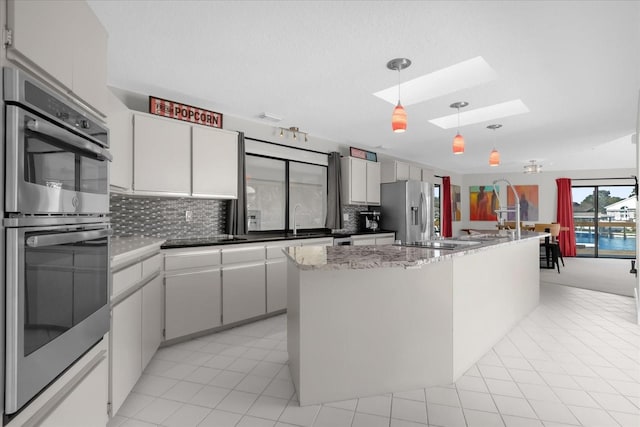 9 Crow Ct, Palm Coast, FL 32137 - kitchen featuring stainless steel appliances, a skylight, backsplash, light tile patterned floors, and decorative light fixtures