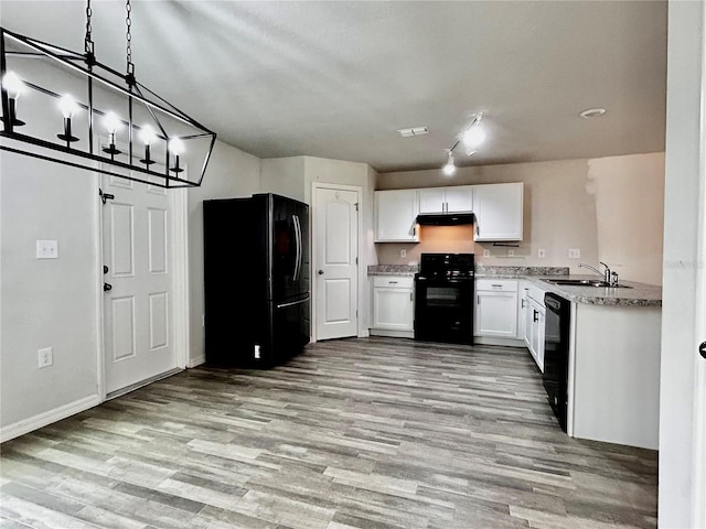 kitchen with black appliances, sink, hanging light fixtures, light hardwood / wood-style flooring, and white cabinetry