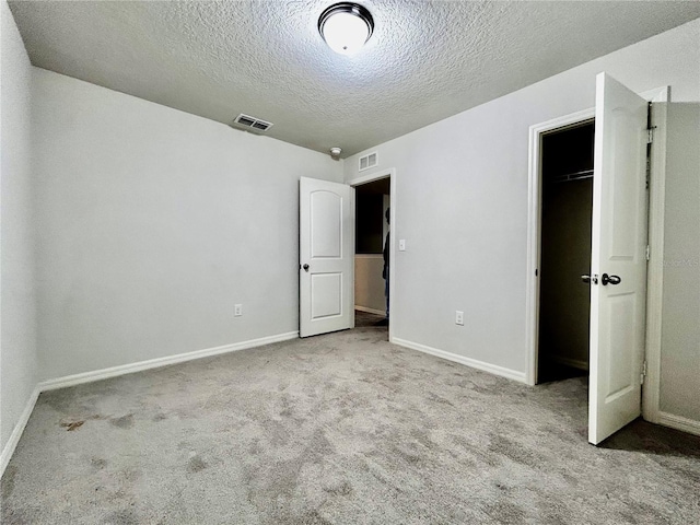 unfurnished bedroom with light colored carpet, a textured ceiling, and a closet