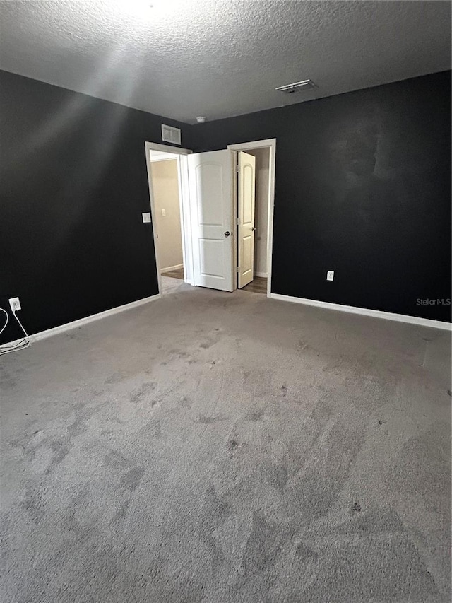 carpeted spare room with a textured ceiling