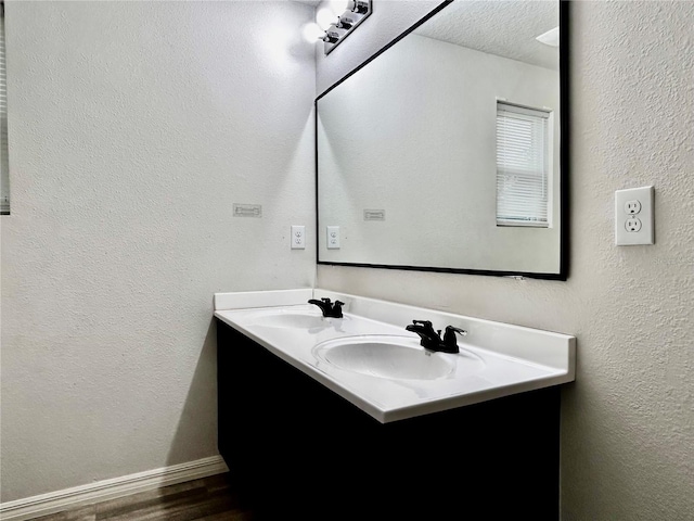 bathroom featuring double vanity, a textured ceiling, a sink, and wood finished floors