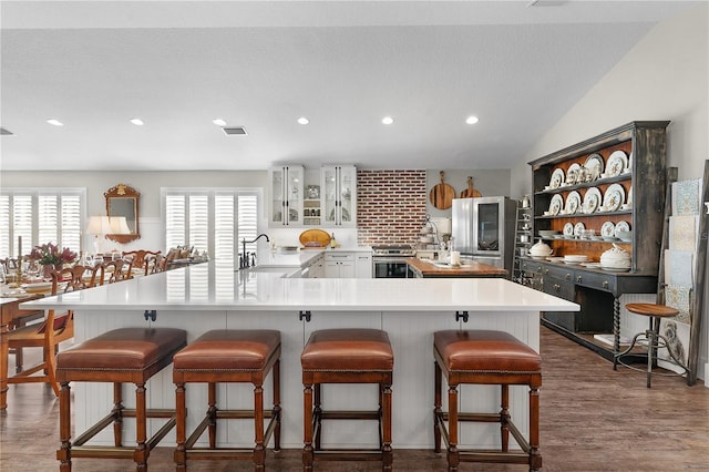 kitchen featuring kitchen peninsula, a kitchen breakfast bar, vaulted ceiling, and sink