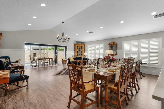 dining space with a notable chandelier, lofted ceiling, wood-type flooring, and a textured ceiling