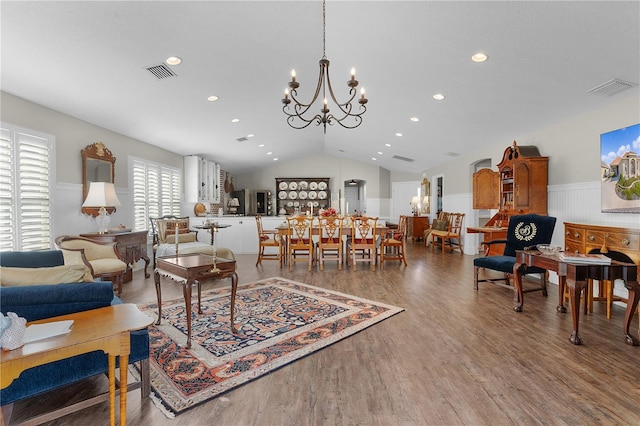 living room with a wealth of natural light, a chandelier, vaulted ceiling, and hardwood / wood-style flooring