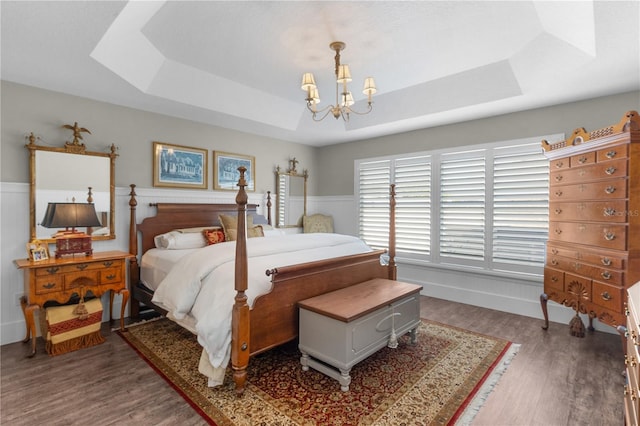 bedroom with a notable chandelier, a raised ceiling, and dark wood-type flooring